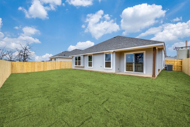 rear view of property with a lawn, central air condition unit, a shingled roof, and a fenced backyard