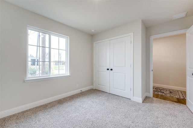 unfurnished bedroom with light colored carpet and a closet