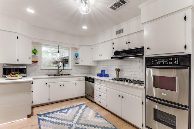 kitchen with stainless steel appliances, light countertops, white cabinets, a sink, and under cabinet range hood