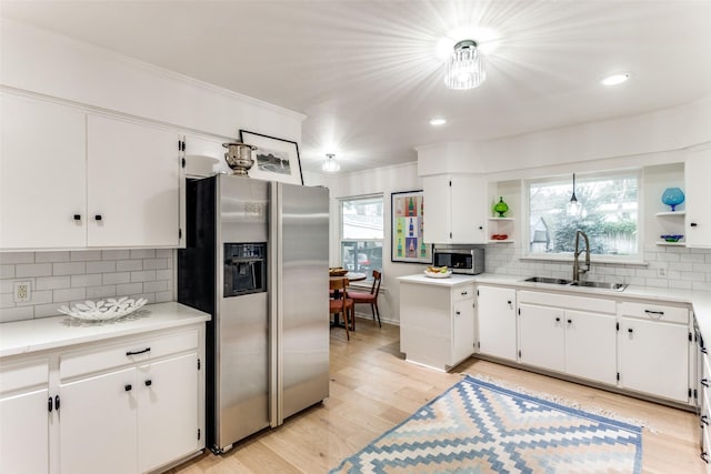 kitchen with stainless steel appliances, a sink, light countertops, and white cabinets