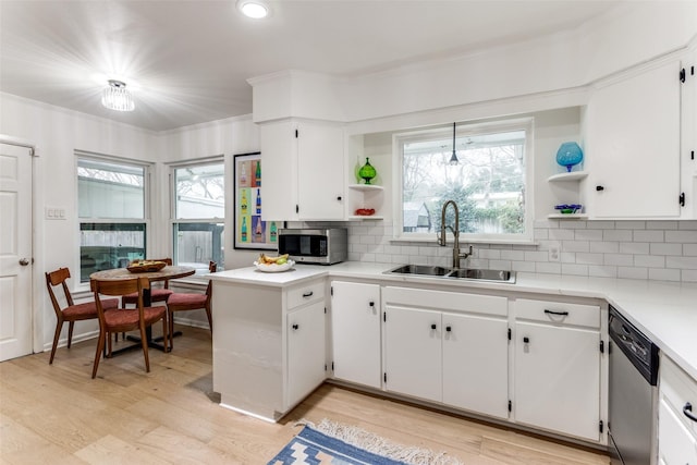 kitchen with white cabinets, decorative light fixtures, light countertops, stainless steel appliances, and a sink