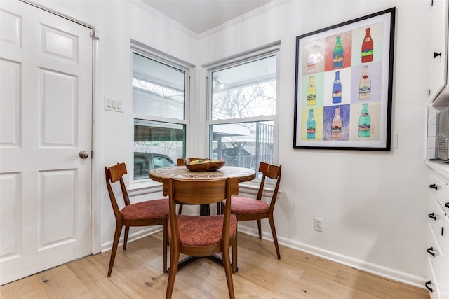 dining area with light wood-type flooring, baseboards, and crown molding