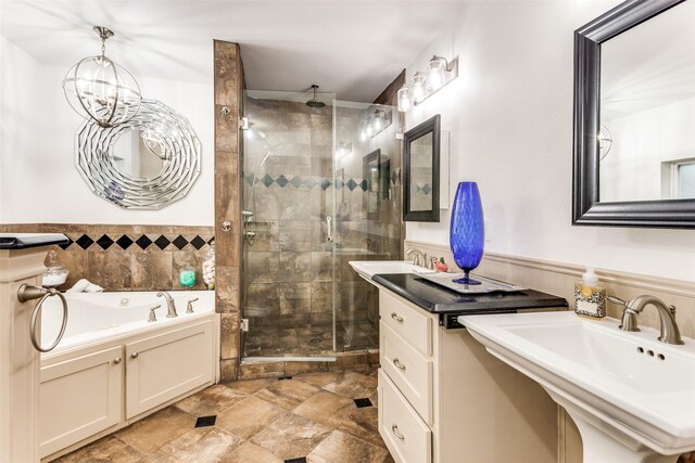 bathroom with a garden tub, a stall shower, wainscoting, and a sink