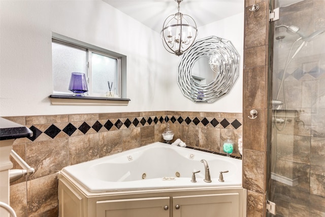 bathroom featuring a whirlpool tub, a chandelier, and a shower with door