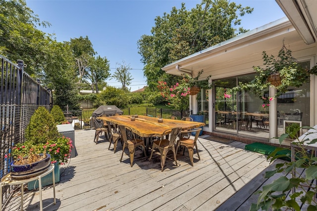 wooden terrace with outdoor dining area, area for grilling, and a fenced backyard