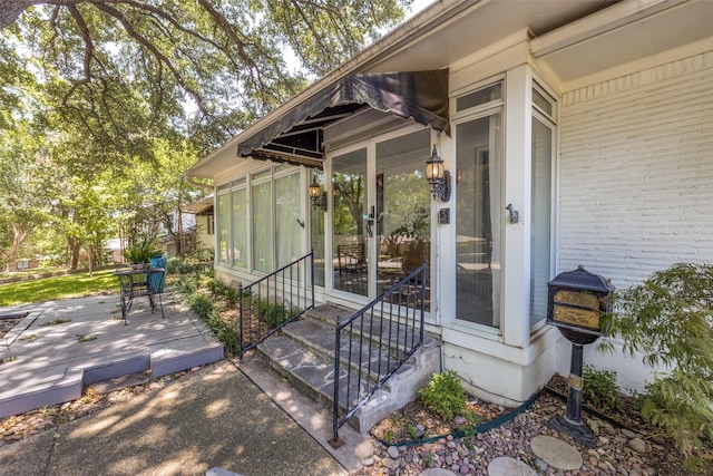 view of exterior entry featuring brick siding and a deck