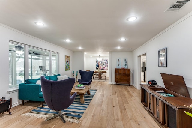 living area featuring recessed lighting, light wood-type flooring, visible vents, and crown molding