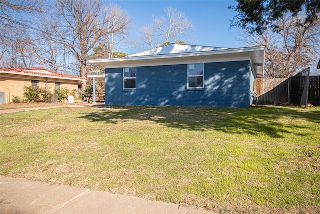 view of property exterior with brick siding, a lawn, and fence