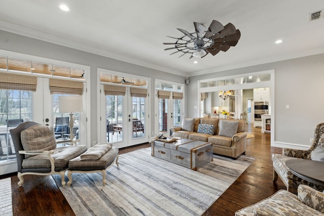 living room with hardwood / wood-style flooring, crown molding, ceiling fan with notable chandelier, and french doors