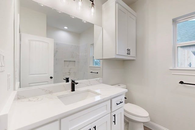 bathroom featuring vanity, a tile shower, and toilet