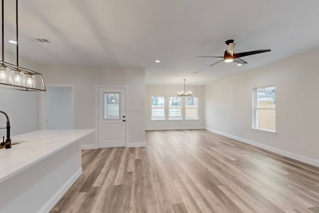 interior space featuring ceiling fan with notable chandelier and light hardwood / wood-style flooring