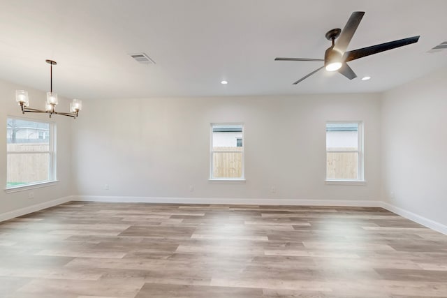 unfurnished room with ceiling fan with notable chandelier and light hardwood / wood-style floors