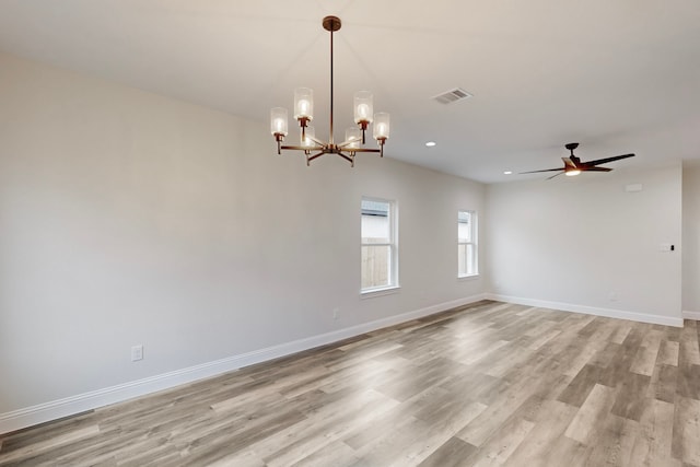 unfurnished room featuring ceiling fan with notable chandelier and light hardwood / wood-style floors