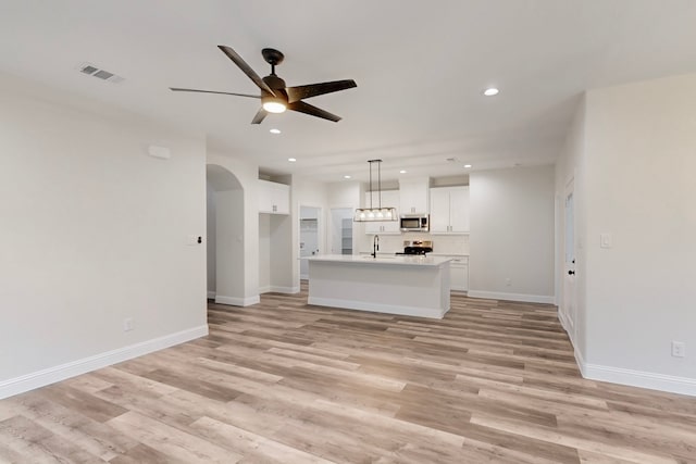 unfurnished living room with ceiling fan, sink, and light hardwood / wood-style floors