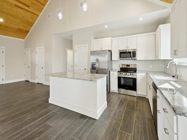 kitchen with sink, appliances with stainless steel finishes, white cabinetry, a center island, and light stone countertops