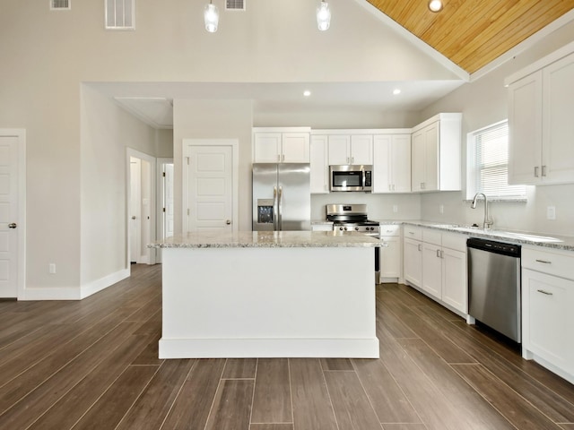 kitchen with white cabinetry, sink, a center island, light stone counters, and stainless steel appliances