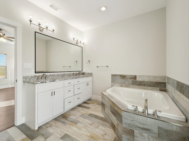 bathroom with hardwood / wood-style flooring, vanity, tiled bath, and ceiling fan