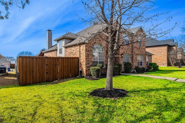 view of home's exterior with brick siding, a chimney, a lawn, fence, and cooling unit