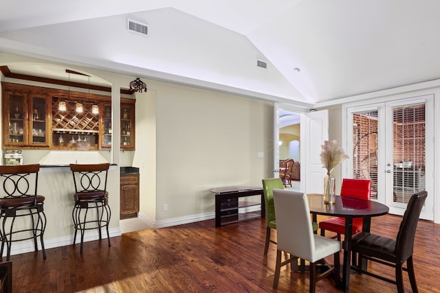 dining space featuring french doors, bar, dark hardwood / wood-style floors, and high vaulted ceiling