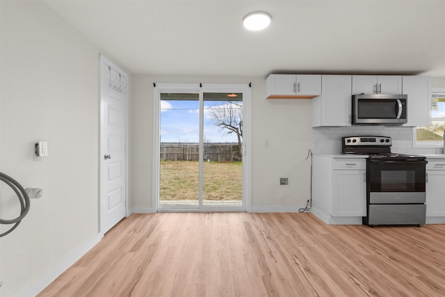 kitchen featuring backsplash, appliances with stainless steel finishes, light hardwood / wood-style flooring, and white cabinets