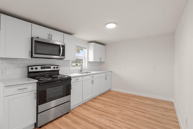 kitchen featuring sink, backsplash, stainless steel appliances, and white cabinets