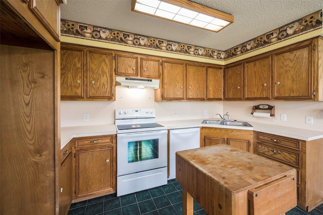 kitchen featuring sink, a textured ceiling, white appliances, and dark tile patterned flooring