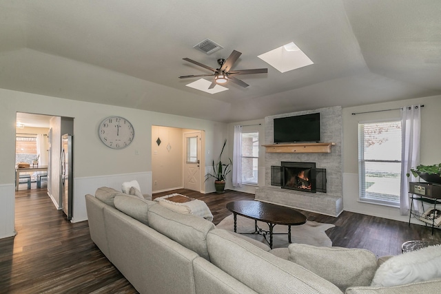 living room with vaulted ceiling with skylight, dark wood-type flooring, and a fireplace