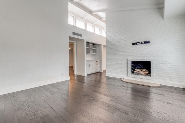 unfurnished living room featuring a fireplace, dark wood-type flooring, high vaulted ceiling, and beamed ceiling