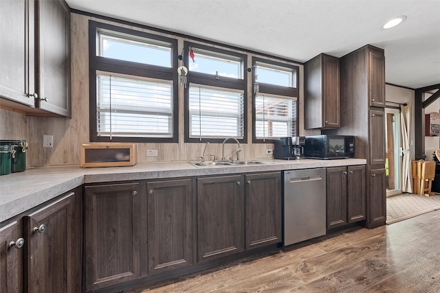 kitchen featuring stainless steel dishwasher, dark brown cabinetry, sink, and light wood-type flooring