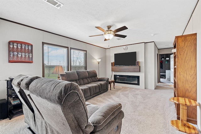 living room with a textured ceiling, ornamental molding, light colored carpet, and ceiling fan