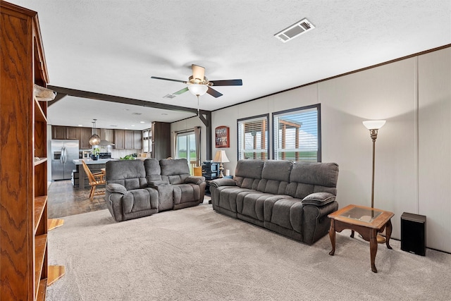 living room featuring ceiling fan, a textured ceiling, and carpet