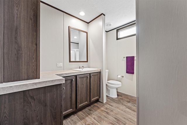 bathroom featuring hardwood / wood-style flooring, vanity, ornamental molding, a textured ceiling, and toilet