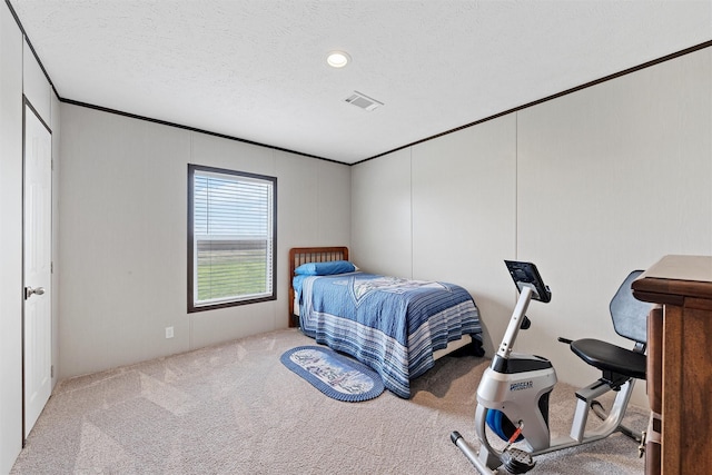 bedroom with ornamental molding, light carpet, and a textured ceiling