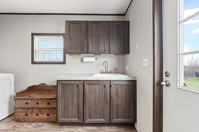 kitchen featuring dark brown cabinetry, sink, washer / dryer, and hardwood / wood-style flooring