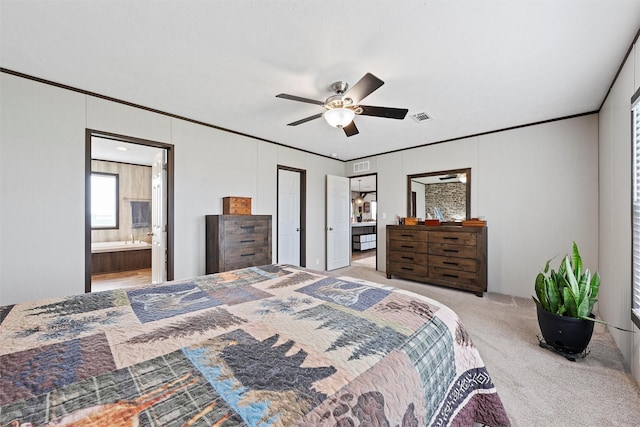 carpeted bedroom featuring crown molding, ensuite bath, and ceiling fan