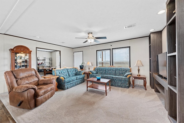 carpeted living room with ornamental molding and ceiling fan