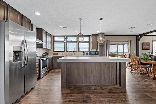 kitchen featuring dark brown cabinetry, sink, hanging light fixtures, a kitchen island, and stainless steel appliances