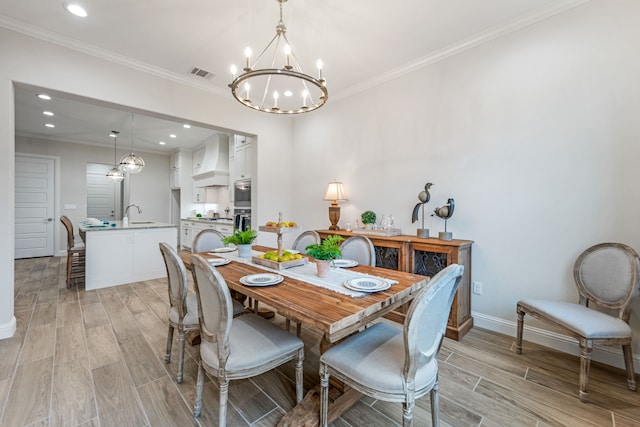 dining room with crown molding, sink, and a chandelier