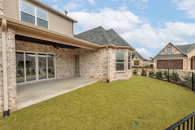 rear view of house featuring ceiling fan, a yard, and a patio