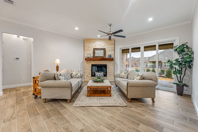 living room featuring ornamental molding, a stone fireplace, and ceiling fan