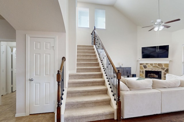 living room featuring a fireplace, ceiling fan, high vaulted ceiling, and tile patterned floors