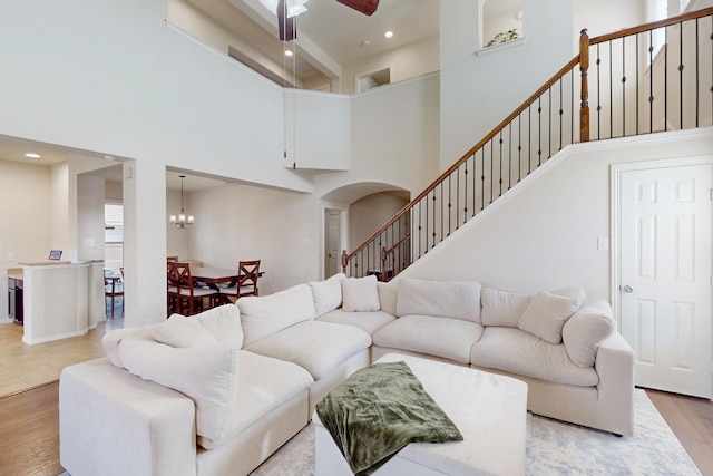 living room featuring hardwood / wood-style floors, ceiling fan with notable chandelier, and a high ceiling