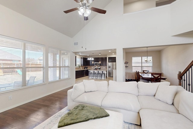 living room with high vaulted ceiling, dark hardwood / wood-style flooring, and ceiling fan with notable chandelier