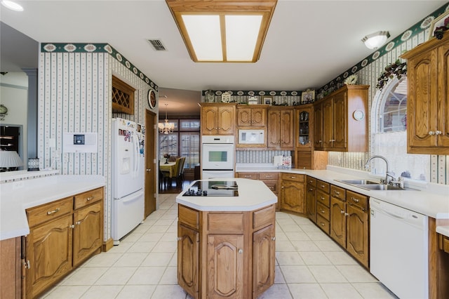 kitchen featuring white appliances, a sink, a kitchen island, visible vents, and wallpapered walls