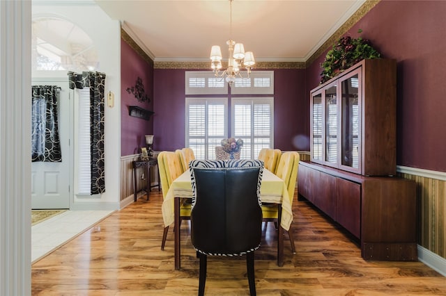 dining area with ornamental molding, a chandelier, and hardwood / wood-style floors