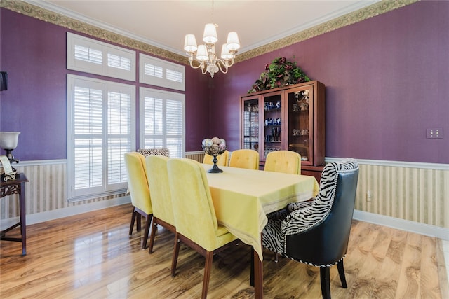 dining space with light wood-type flooring, a notable chandelier, and ornamental molding