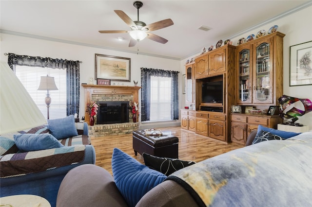 living room with ceiling fan, ornamental molding, a brick fireplace, and hardwood / wood-style floors