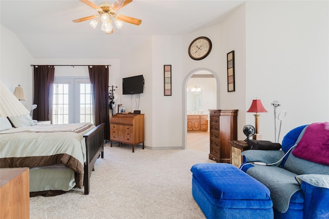 carpeted bedroom with vaulted ceiling, ceiling fan, and ensuite bath