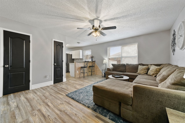 728 Oriole Dr, Saginaw, TX 76131 - living room with light wood-type flooring, ceiling fan, baseboards, and a textured ceiling