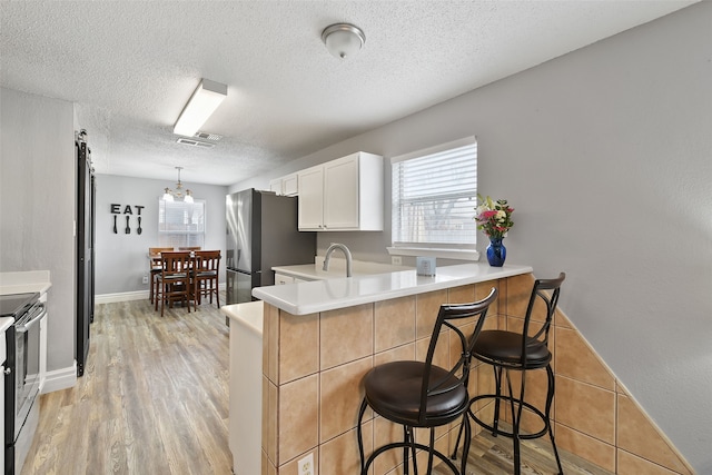 728 Oriole Dr, Saginaw, TX 76131 - kitchen featuring light countertops, a breakfast bar area, a peninsula, and white cabinets